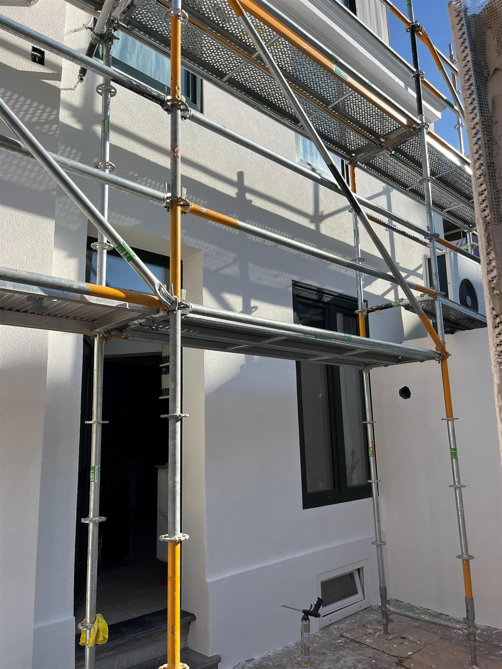 Façade en cours — crépi et échafaudage vue latérale